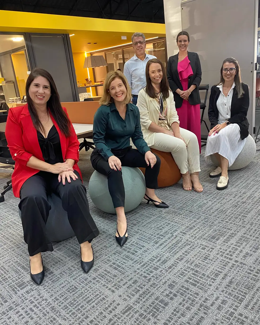Convidadas e anfitriões sentados em bolas de ergonomia no showroom da Klips