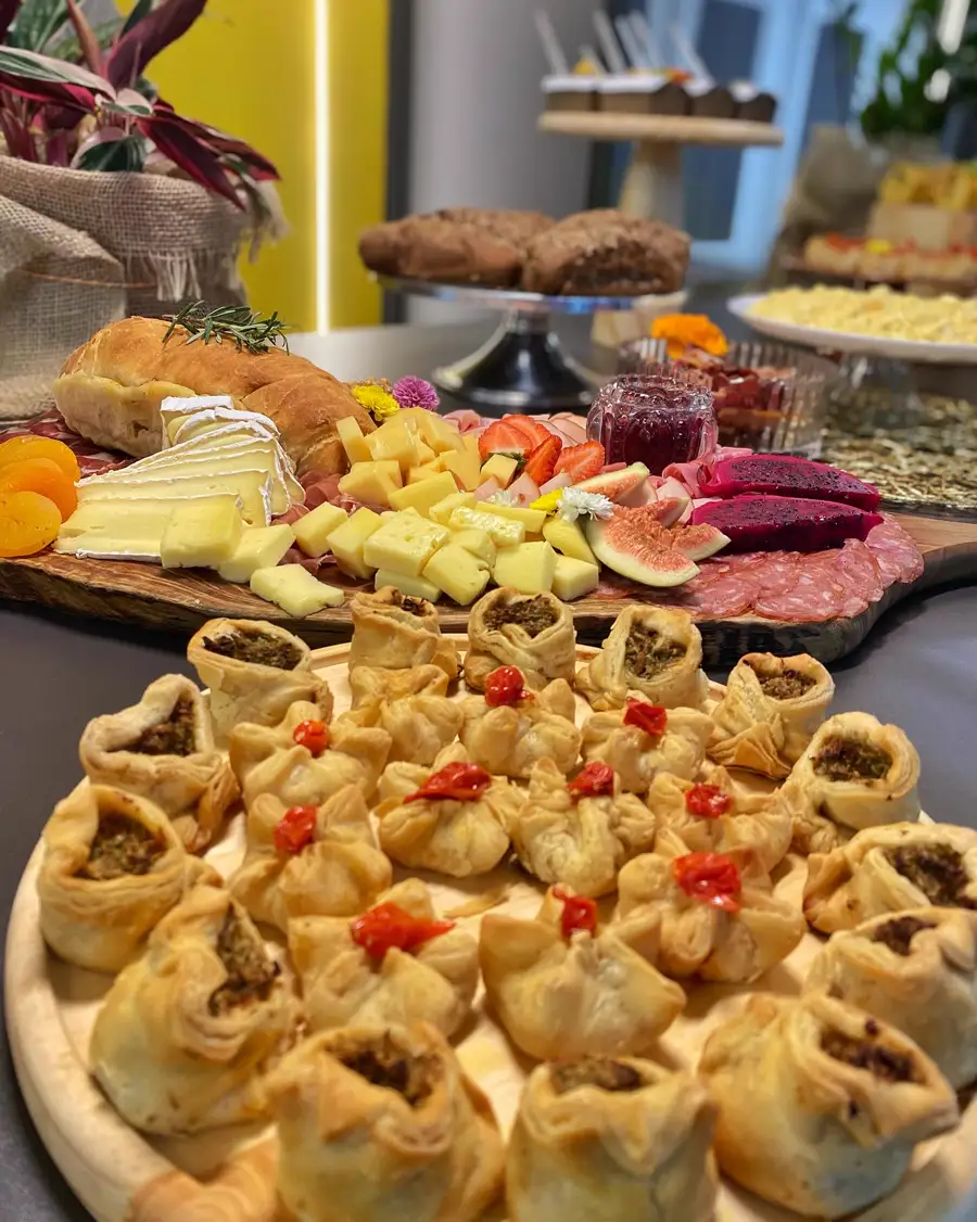 Mesa de coffee com queijos, folhados e frutas no showroom da Klips