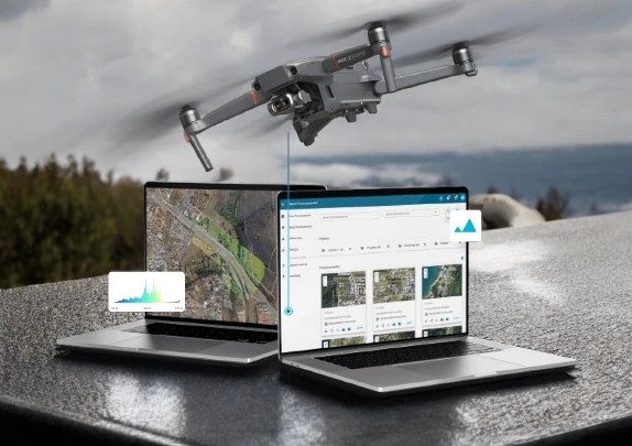 Drone sobrevoando dois notebooks com a plataforma da Mappa.ag processando imagens aéreas em mapas