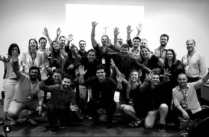 Time da Hello reunido, de braços erguidos, em foto preto e branco